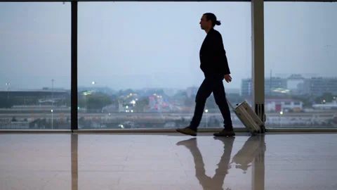 Smart casual dressed man walk at empty airport terminal with suitcase Stock Footage 320118436
