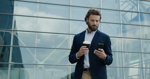 Smart casual dressed Office Worker is drinking Coffe and using his Phone.  Stock Footage 117688692