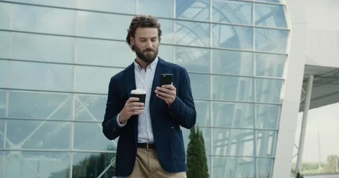 Smart casual dressed Office Worker is drinking Coffe and using his Phone. Man is Stock Footage 146491728