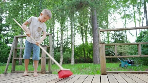 Smart Child Boy Cleaning and Sweeping the Balcony. Taking Care of his Home Yard  Video stock 133769879