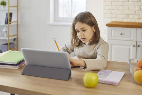 Smart child using tablet to read and study online, busy school student doing Stock Photos