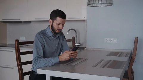 Smart confident man is sitting at the table and chatting using smartphone. 스톡 동영상 105113833