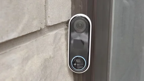 Smart doorbell camera mounted on a stone wall, showcasing its sleek design and Stock Footage 332578493