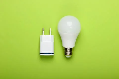 Smart energy-saving light bulb with a charger on a green background. Top view Stock Photos