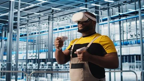 Smart factory engineer using VR headset to oversee operation of robotic arms Stock Photos