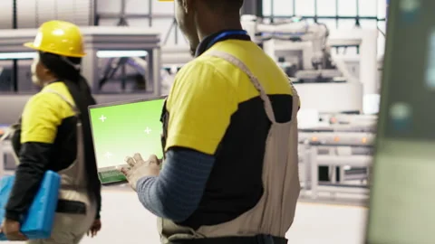 Smart factory mechanic testing automated systems using isolated screen laptop Stock Footage 307360698
