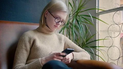 Smart girl with glases using smartphone installing social app and publishing Stock Footage 103286259