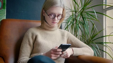 Smart girl with glases using smartphone installing social app and publishing Stock Footage 103286496