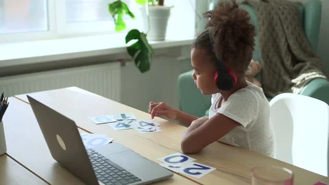 Smart girl learning mathematics in front of laptop and sitting at table in Stock Footage 169014723