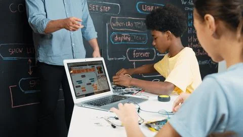 Smart girl programming system while african student fixing robot. Edification. Foto stock