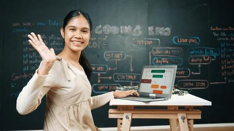 Smart girl waving to camera while programing code at blackboard. Edification. 스톡 사진