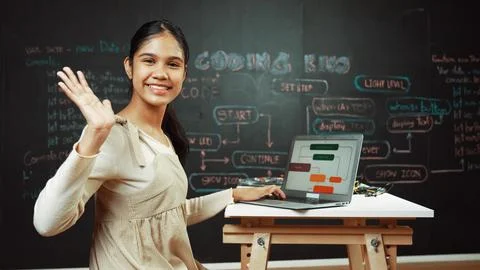 Smart girl waving to camera while programing code at blackboard. Edification. Stockfoto's