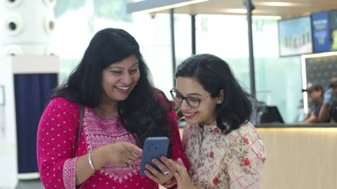 Smart girls using mobile phone standing in shopping mall. Stock Footage 245296420