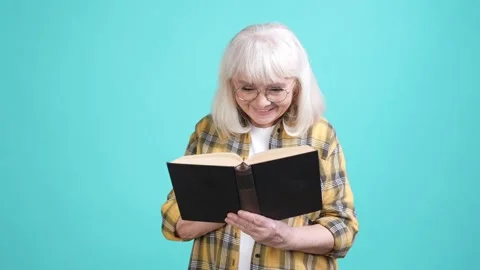 Smart granny free time read interesting book isolated cyan color background Video stock 170533754