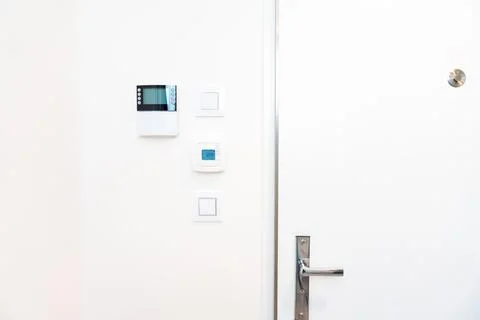Smart home control panel and thermostat on white wall in modern interior Stock Photos