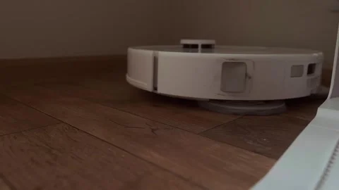 Smart home technology in action robot vacuum cleans the floor during the day Stock Footage 314642274
