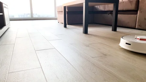 Smart House. Vacuum cleaner robot runs on wood floor in a living room Stock Footage 111983684