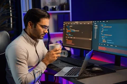 Smart IT developer drinking coffee cup while working code on pc screen. Surmise. Stockfoto's