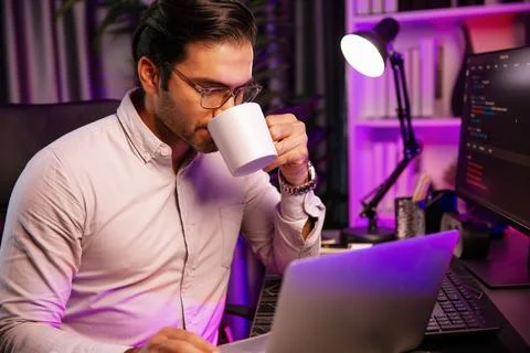 Smart IT developer drinking coffee cup while working code on pc screen. Surmise. Stock Photos