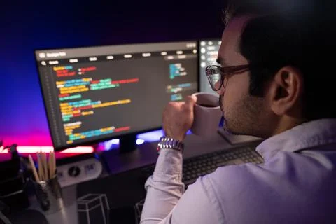 Smart IT developer drinking coffee cup while working code on pc screen. Surmise. Stock Photos