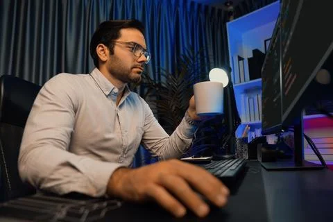 Smart IT developer drinking coffee cup while working code on pc screen. Surmise. Stock Photos