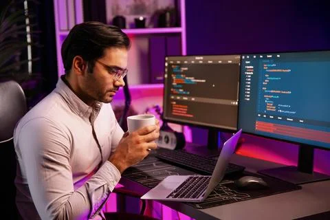 Smart IT developer drinking coffee cup while working code on pc screen. Surmise. Stock Photos