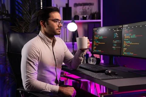 Smart IT developer holding coffee cup with pose at neon light office. Surmise. Stock Photos