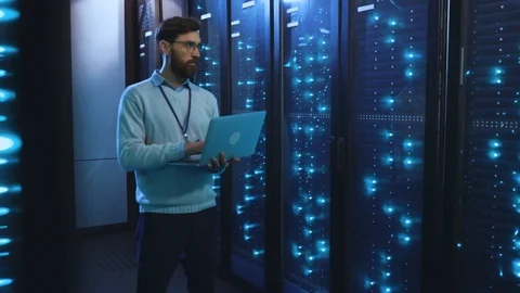 Smart IT specialist with notebook controlling rack server cabinet in big Stock Footage 118450036