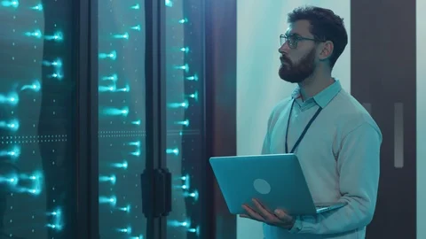 Smart IT specialist running rack server diagnostics on laptop computer in data Stock Footage 119233380