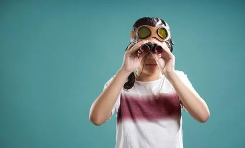 Smart kid using binoculars facing camera . Stock Photos