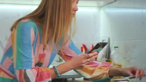 Smart kitchen control, woman controls kitchen appliances using her smartphone Stock Footage 323797446