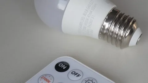 Smart LED bulb with remote control on white surface Stock Footage 315124726