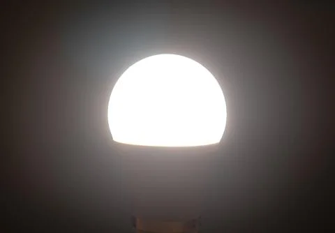 Smart LED Light Bulb Glowing White in Dark Interior Stock Photos