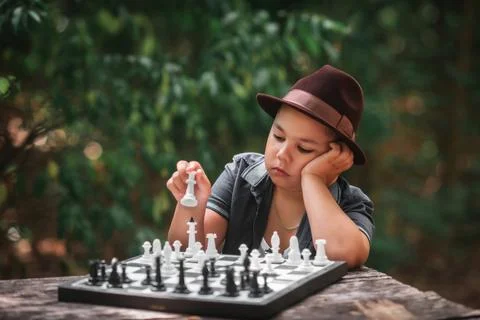 Smart little boy playing chess outdoors in nature. Foto stock