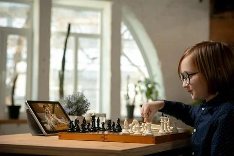 Smart little Caucasian boy chess player playing chess online using laptop. Stock Photos