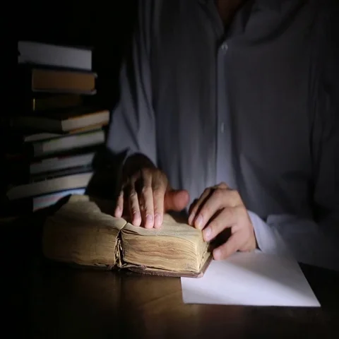 Smart man studying late at night, he is sitting at desk and reading book Stock Footage 69396047