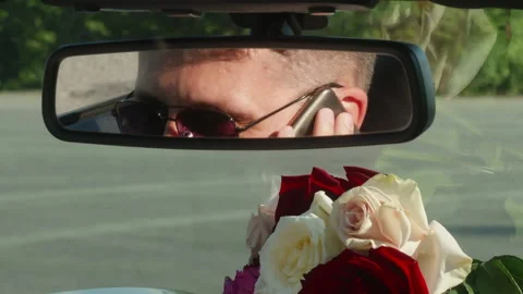 Smart man talking on smartphone reflecting on rear view mirror of car Видео 266492433