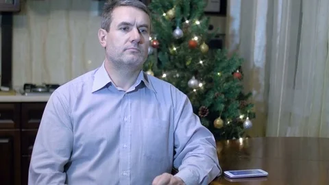 Smart middle aged man talking on mobile phone sitting at table at home on Stock Footage 70701521