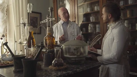 Smart old Caucasian man talking with young new employee in ancient pharmacy Stock Footage 120721955