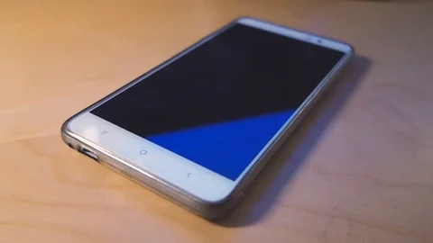 Smart phone with blank screen lying on wooden table Stock Footage 77577931