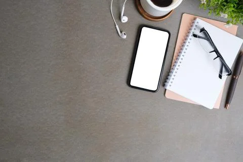 Smart phone with blank screen, notebook, coffee cup and earphones on grey b.. Stock Photos