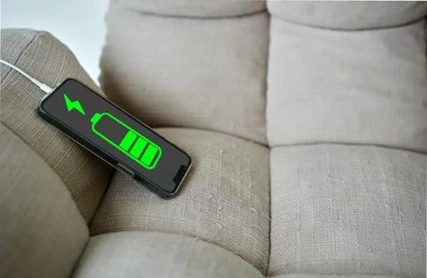 Smart phone connect charging on sofa with battery graphic icon status Stock-Fotos
