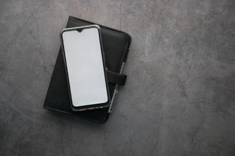 Smart phone with empty screen and a diary on gray background Foto stock