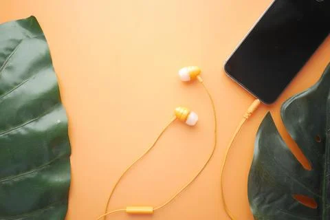 Smart phone with empty screen, earphone on orange background Stock Photos