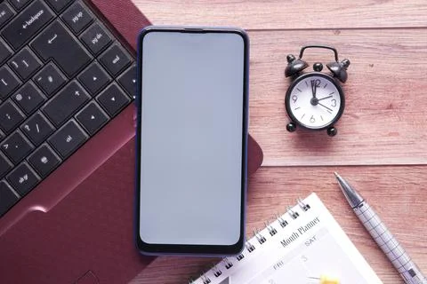 Smart phone with empty screen, laptop on wooden background Stock Photos