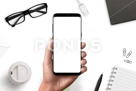 Smart phone in man hand mockup above office desk PSD Template