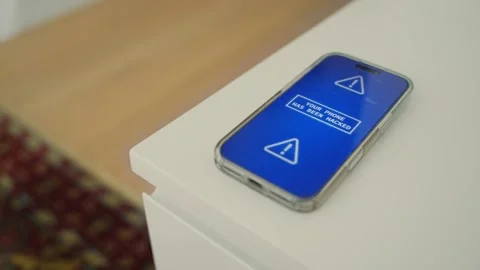 Smart phone on night stand or table with alert of cyber hacker attack or virus Видео 329378675