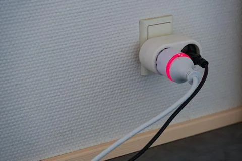 Smart power plug with red indicator light in wall socket at home Stock Photos