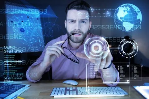 Smart programmer frowning while biting his glasses and pointing to the screen Stock-Fotos