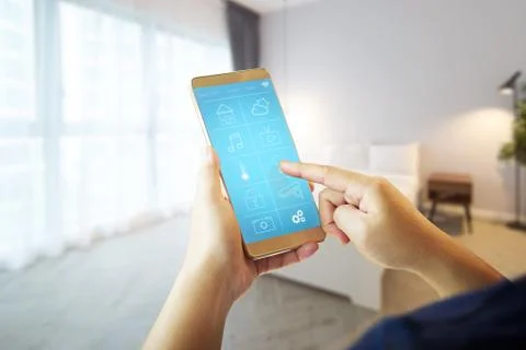 Smart remote home control system apps on a hand phone with blur house  interi Stock Photos